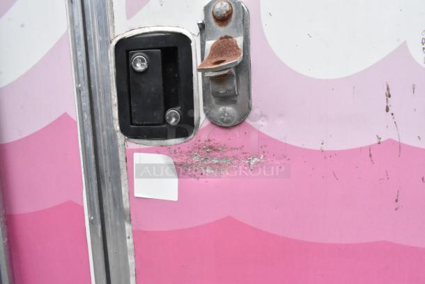 Pink food trailer door with rusted metallic latch and black handle, minor surface wear visible.