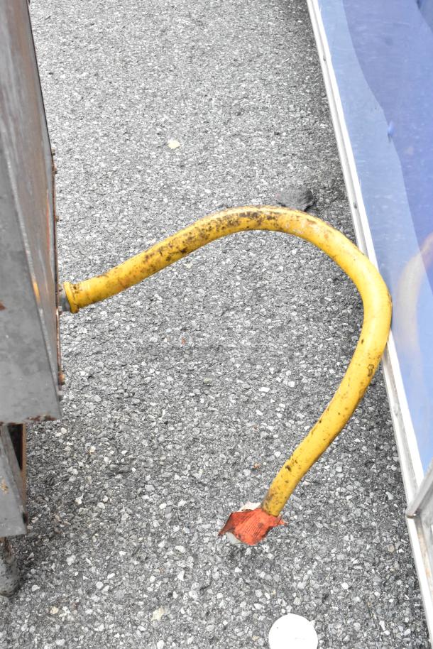 Yellow hose on concrete surface, appears worn with rust-colored markings on a protruding metal end. No fryer visible.