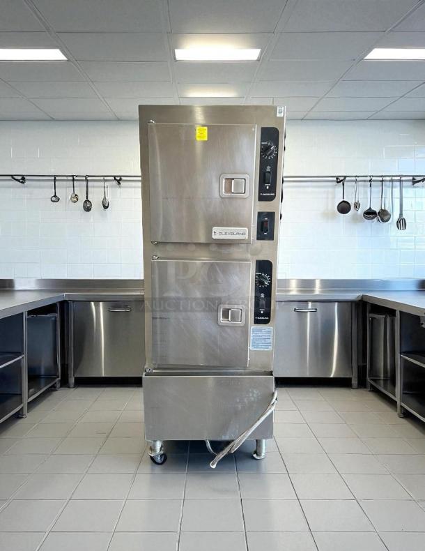 Commercial stainless steel steamer in kitchen, Cleveland brand, dual compartments, dial controls, mounted on wheels, excellent condition.