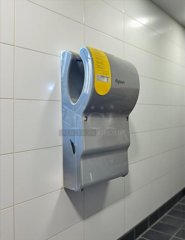 Dyson Airblade hand dryer, model 13043-01, silver, wall-mounted, perfect condition, yellow label with instructions visible.