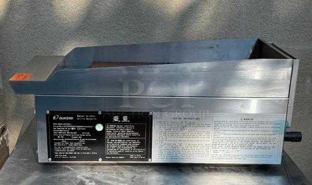 Dukers Gas Steel Countertop Griddle DCGM12 with labels indicating model, safety certifications, and lighting instructions.