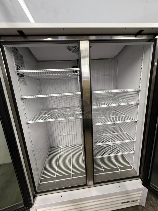 TRUE FLM-54F-TSL01 two-door freezer merchandiser, full length, clean interior, white wire shelving, stainless steel frame.