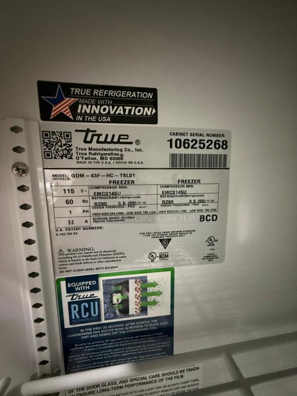 TRUE FLM-54F-TSL01 Full Length Freezer Merchandiser, two-section, USA-made, model and serial number labels visible.