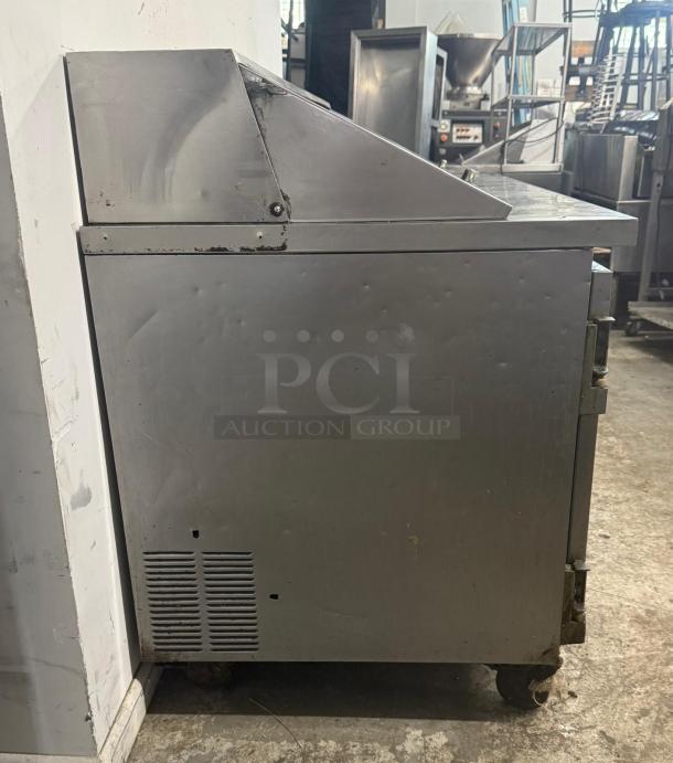 Leader commercial undercounter 3-door refrigerator, stainless steel. Visible wear, on casters, suitable for worktop use.
