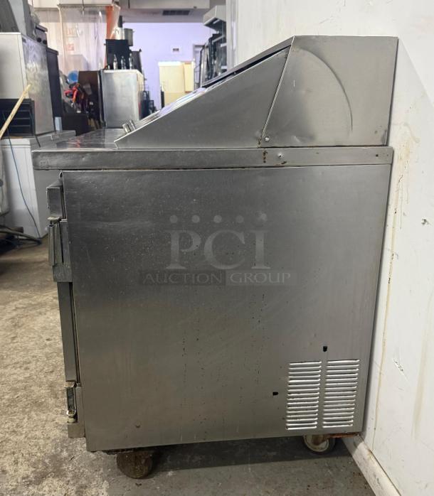 Leader commercial undercounter 3-door refrigerator, stainless steel, used condition, worktop lowboy design, casters visible.