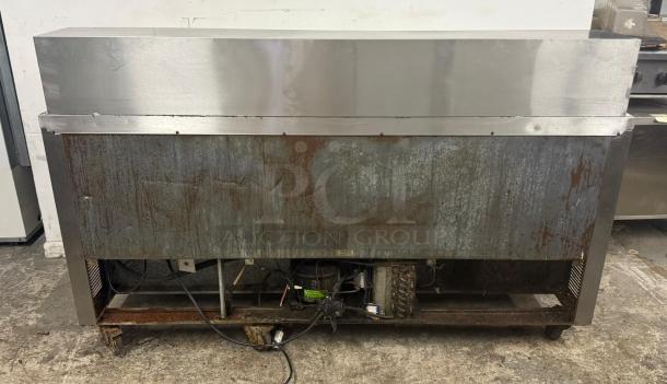 Leader Commercial Undercounter 3-Door Refrigerator; stainless steel, worktop, visible wear and rust, refrigeration components exposed.