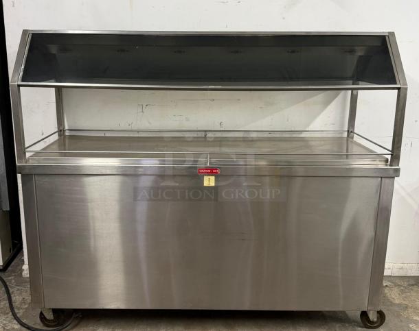 Stainless steel buffet warmer with sneeze guard and labeled "Caution - Hot," on wheels. Good condition.