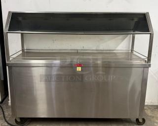 Stainless steel buffet warmer with sneeze guard and labeled "Caution - Hot," on wheels. Good condition.