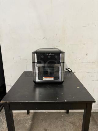 Instant Pot Vortex Plus 10, 7-in-1 Air Fryer Toaster Oven, Black/Stainless Steel, 1500W, on a table, front view.