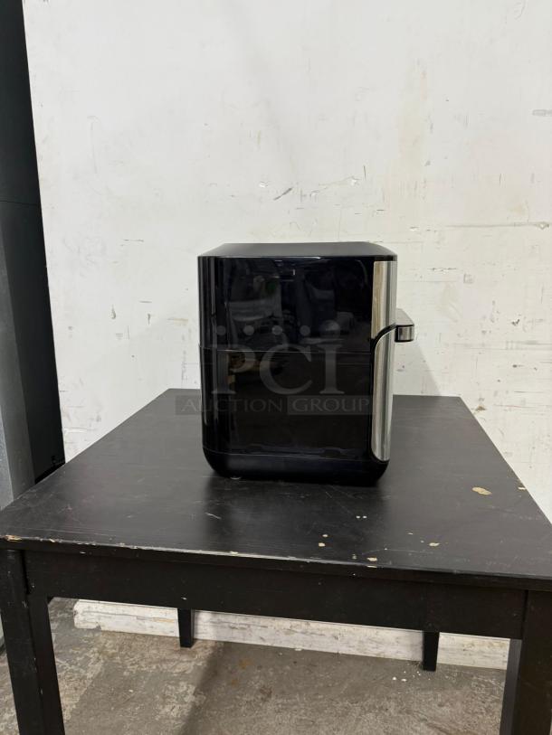Instant Pot Vortex Plus 10, 7-in-1 air fryer toaster oven combo in black and stainless steel on a table.