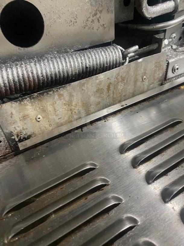 Garland H283 stainless steel gas range, showing worn metal surface and spring mechanism, highlighting industrial use.