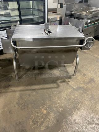 Stainless steel natural gas-powered tilt skillet/braising pan on legs, commercial-grade, with control wheel.