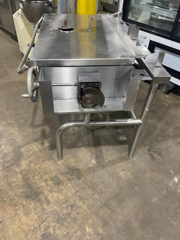 Commercial stainless steel natural gas-powered tilt skillet with legs, visible gear mechanism, and sturdy construction.
