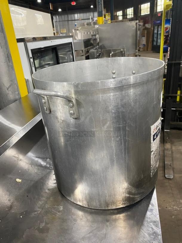 Winco commercial aluminum stock pot, wide base, with dual riveted handles; visible wear; ideal for high-capacity cooking.