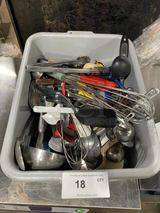 Lot of assorted commercial kitchen utensils in a bin, including whisks, ladles, tongs, and spoons. Mixed condition.