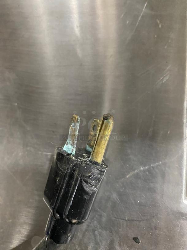Close-up of a worn, corroded electrical plug on stainless steel background for a Servolift refrigerated salad bar.
