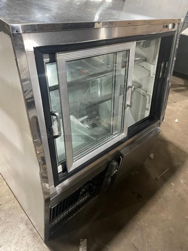 Custom Cool stainless steel deli merchandiser display with slanted glass, double sliding doors, and lower storage compartment.