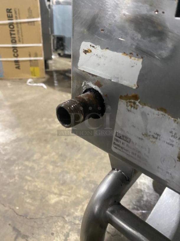 WoodStone stainless steel natural gas countertop plancha griddle with back and side splash, mounted on a single undershelf cart with casters. Visible wear, with labels and a pipe fitting shown.