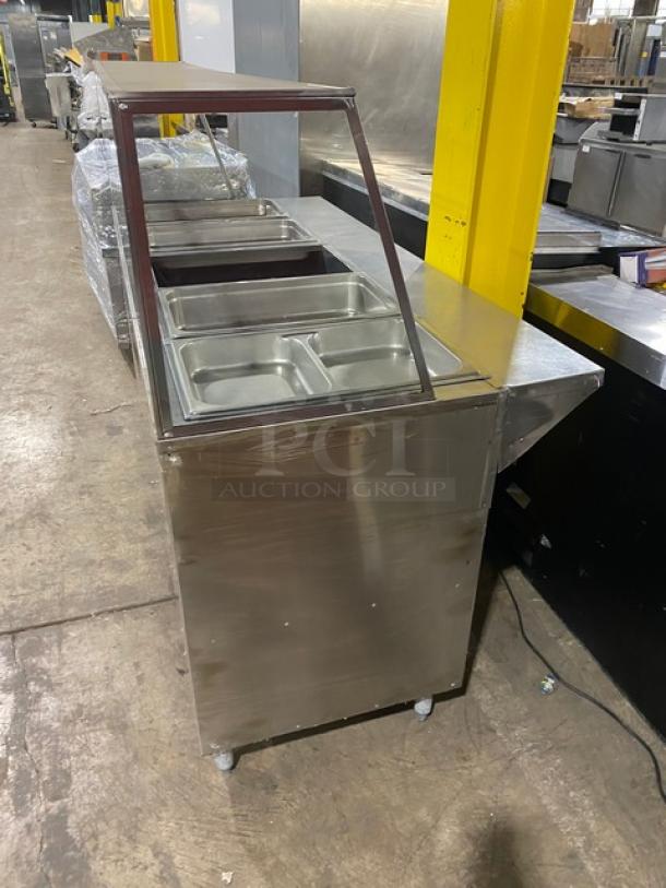 Stainless steel 5-bay steam table with sneeze guard, rear tray-slide, enclosed double shelf base, and legs. Comes with hotel pans.