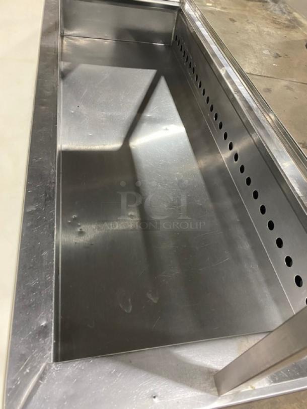 Commercial stainless steel prep table with 2 doors, cutting board, overhead shelf, sneeze guard, wired racks, on legs.