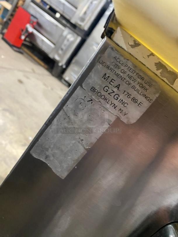 Commercial stainless steel refrigerated prep table with cutting board, overhead shelf, sneeze guard, wire racks, on legs.