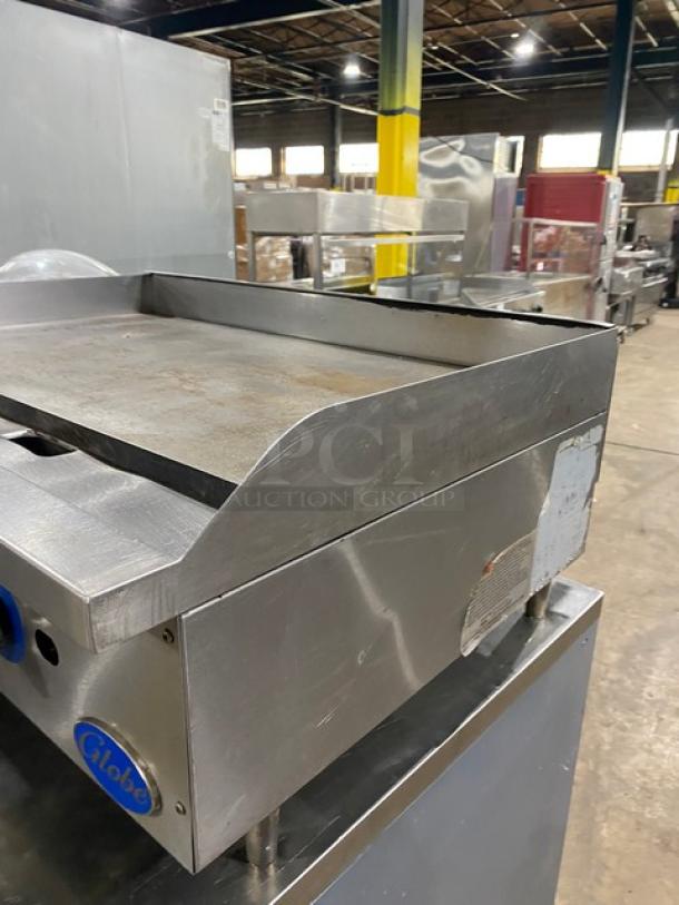 Globe stainless steel natural gas countertop flat griddle with back and side splash, on legs, used condition.
