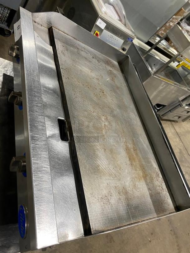 Globe commercial stainless steel natural gas flat griddle with back and side splash, on legs. Used condition.