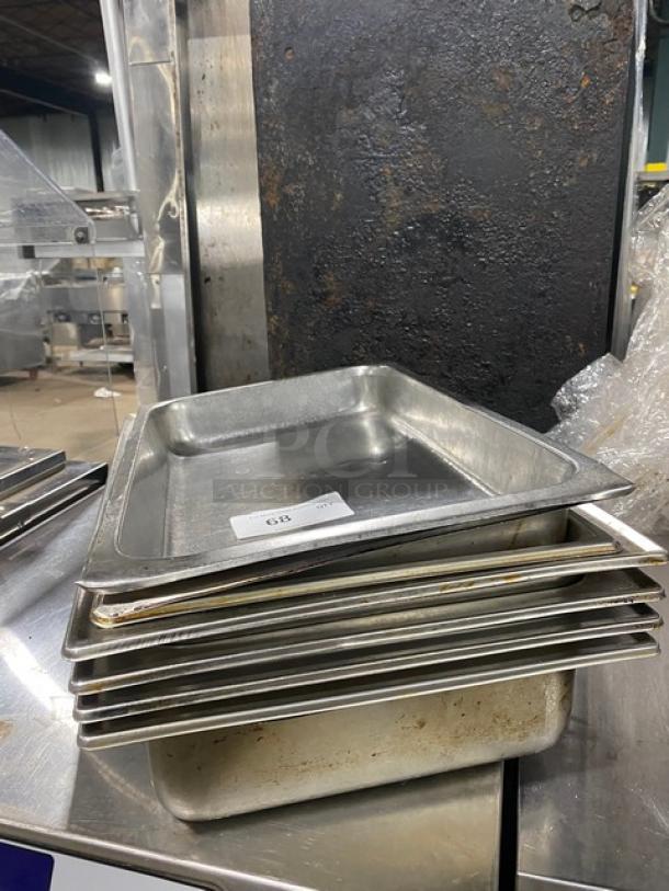 Lot of commercial stainless steel hotel pans in used condition. Includes multiple steamtable pans, stacked, with visible wear.