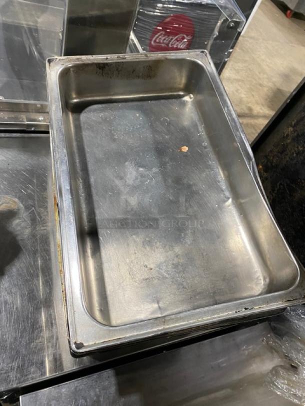 Lot of commercial stainless steel hotel pans, showing signs of use. Ideal for steam tables in catering or restaurant settings.