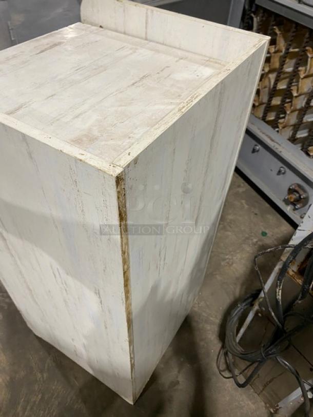 Commercial wooden trash cabinet, enclosed style, white finish with visible wear, corner scuffs, industrial setting.