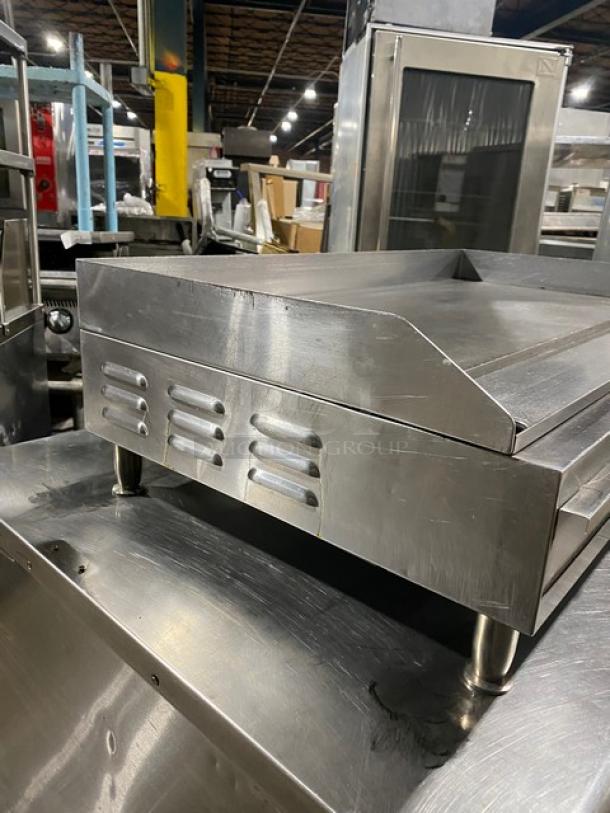 Commercial stainless steel electric countertop flat griddle with back and side splash, on legs. Appears in good condition.