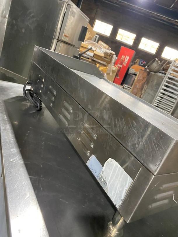 Commercial stainless steel electric countertop flat griddle with back and side splash, on legs, showing some scratches.