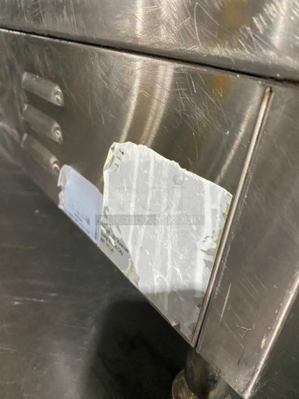 Commercial stainless steel electric countertop flat griddle with back and side splash, on legs. Visible wear on surface.