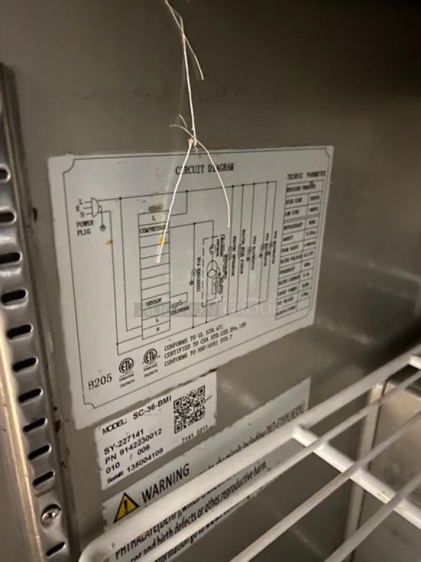 Universal Coolers SC-36-BMI refrigerated prep table with stainless steel construction, cutting board, and wire rack. Model label visible.