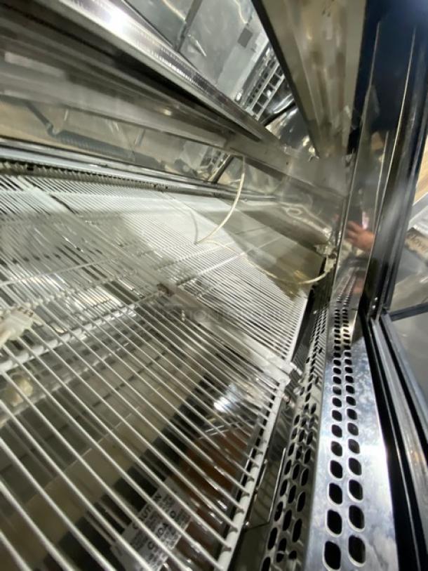 Carrier Tyler Series curved glass refrigerated deli display, stainless steel shelving, poly-coated racks, rear glass doors.