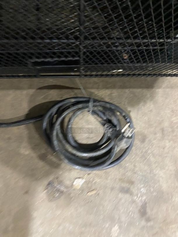 Coiled power cord for Maxx Cold MXM2-48RS refrigerator on concrete floor. Black casing, plug attached.