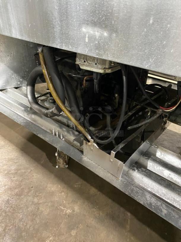 Leader LS72SC commercial refrigerator undercarriage view, highlighting piping and components. Stainless steel finish, on casters.