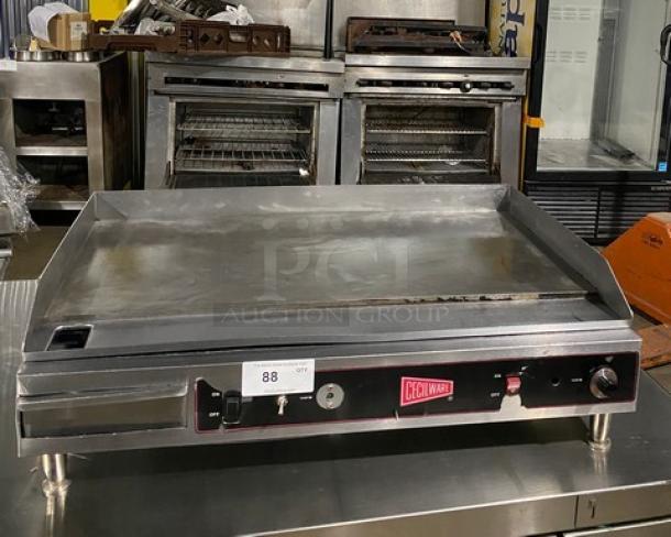 Cecilware commercial stainless steel electric countertop flat griddle with thermostatic control, back and side splash, on legs.