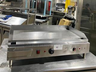 Commercial stainless steel electric countertop flat griddle with back and side splash, on legs, in used condition.