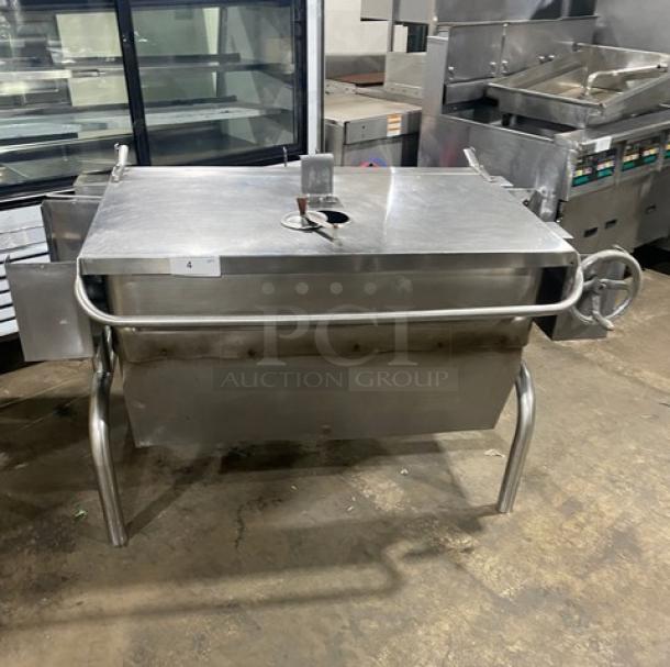 Commercial stainless steel natural gas tilt skillet with hand crank, on legs. Used condition, ideal for large-scale cooking.