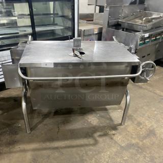 Commercial stainless steel natural gas tilt skillet with hand crank, on legs. Used condition, ideal for large-scale cooking.