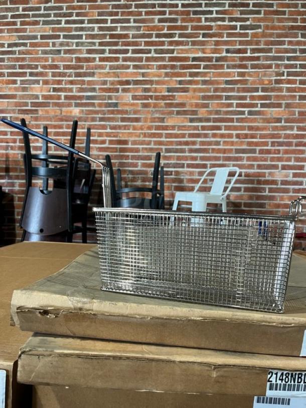 Brand new commercial stainless steel fry basket with front hook and non-slip grip handle on cardboard box.