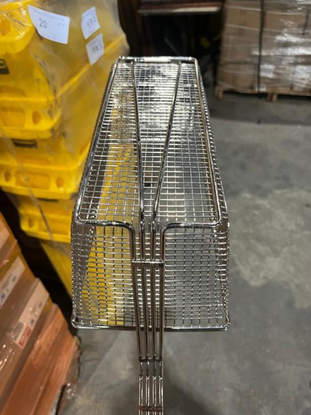 Brand new commercial stainless steel fry basket with front hook and non-slip grip handle, shown in warehouse setting.