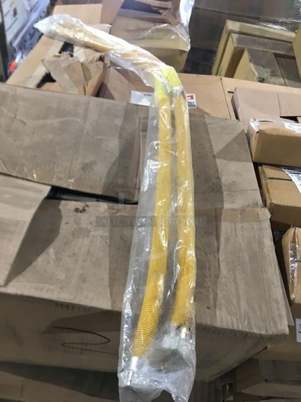 Mixed pallet with various commercial kitchen items, including a yellow gas connection hose in packaging, on cardboard boxes.