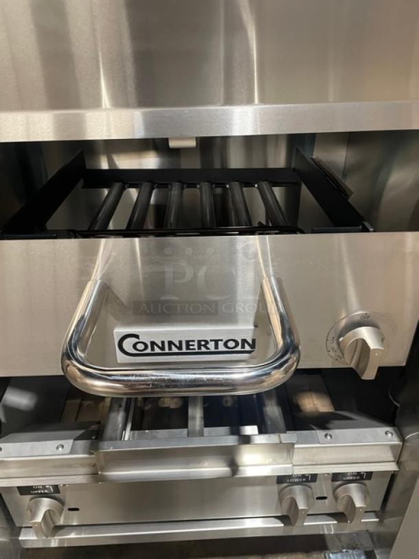 Brand new Connerton A1F stainless steel griddle/broiler combo, gas-powered, polished finish, on casters, visible Connerton logo.