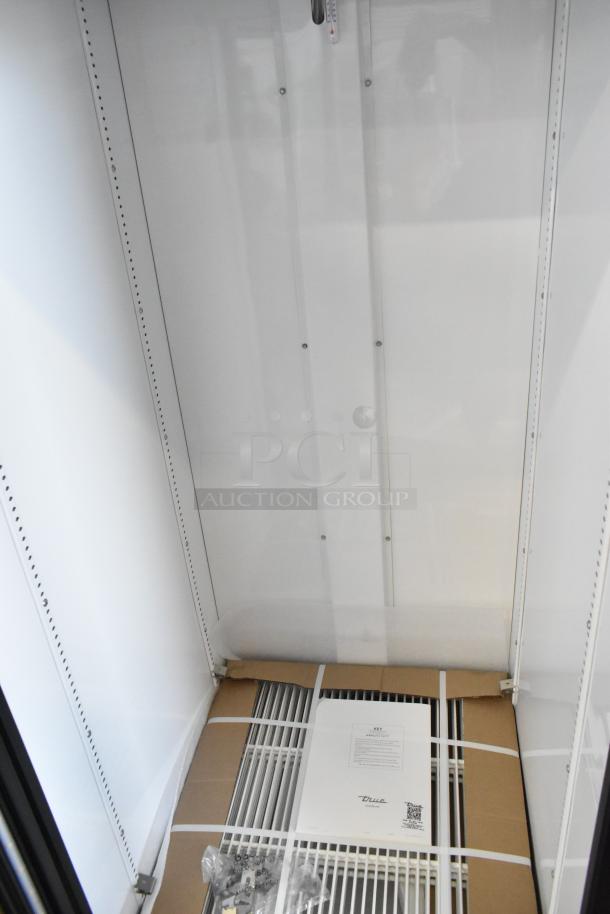 New True GDM-23-HC Cooler Merchandiser with poly coated racks, 115V, 1 phase; indentation visible. Tags with specs shown.