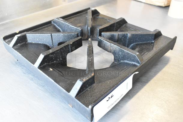 Brand new 12" x 12" cast iron spider grate with scratches. Open top design, built-in bowl. Auction tag visible.