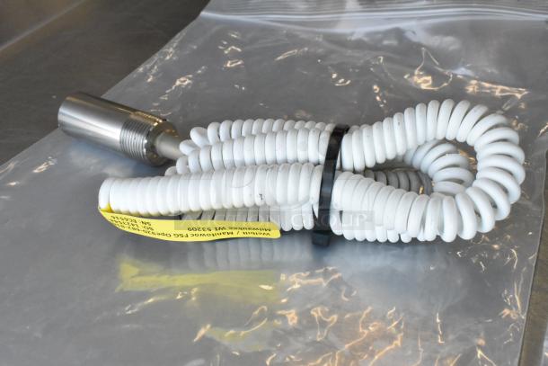 White coiled Manitowoc FSG cord, brand new, labeled with manufacturer details, on clear plastic bag.