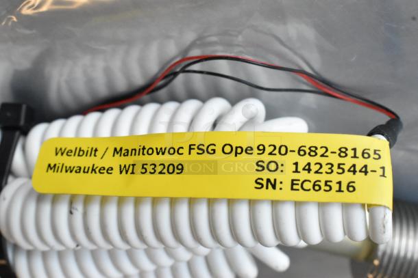 Coiled Manitowoc FSG Cord with yellow label showing contact info, part numbers, and serial number: 1423544-1, EC6516.