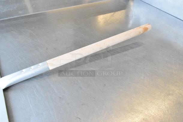 Brand new metal pizza peel with wooden handle, scratch and dent condition, ideal for pizza enthusiasts.